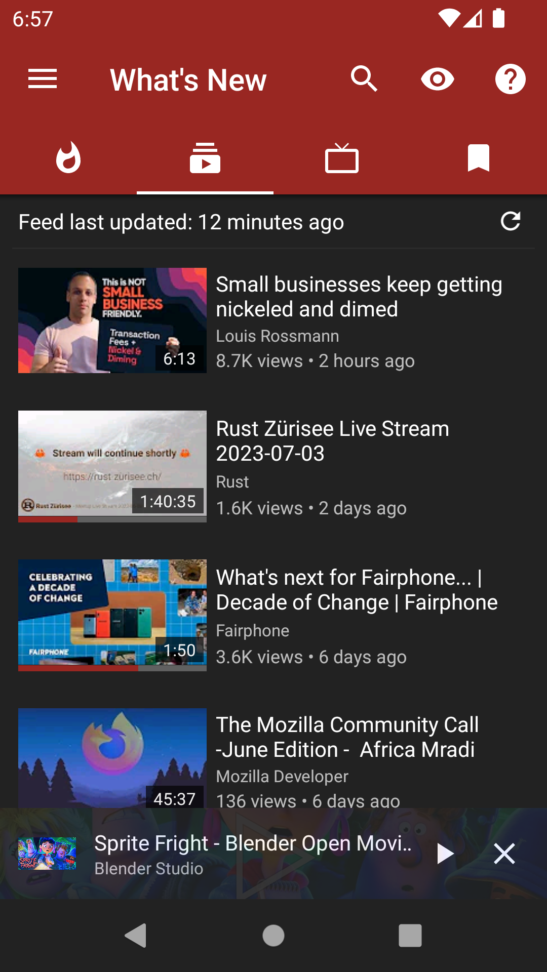 NewPipe: Pestana What's New de NewPipe con el feed de suscripciones y el reproductor en miniatura abajo.